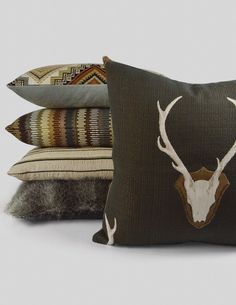 three pillows with deer head on them, one is brown and the other is white