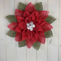 a red and green christmas wreath hanging on a white wooden wall