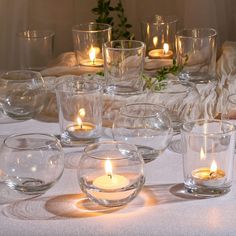 a table topped with lots of glass bowls filled with candles