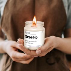 a person holding a candle in their hands with the word scorpio on it