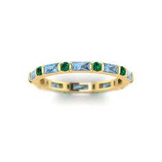 a yellow gold band with blue and green stones on the sides, set against a white background