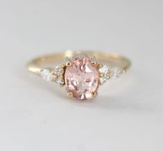 an oval pink diamond ring with three small diamonds around it