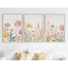 three floral paintings hanging on the wall above a white couch