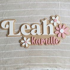 a wooden name sign with flowers and the word leah karmile on it