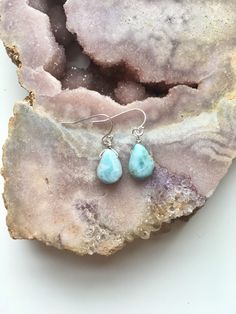 "A beautiful dainty polished and drilled pair of Larimar in a simple tear drop shape will be placed on a dainty sterling silver or 14k gold filled ear hooks. These Larimar earrings have the most beautiful soothing blue shades. With its light blue and white swirls this will make the perfect piece of Larimar jewelry in your collection. Each pendant differs from the next they are about 1/2\" 💙 sea and sky energies 💙 serenity 💙 relaxation 💙 worry stone 💙 emotional cleanser and healer 💙 helps r Teardrop Pendant Gemstone Earrings For Gift, Gemstone Teardrop Pendant Earrings Gift, Blue Teardrop Pendant Earrings As Gift, Dainty Teardrop Gemstone Earrings, Hypoallergenic Pear-shaped Earrings Gift, Pear-shaped Earrings With Ear Wire As Gift, Pear-shaped Earrings With Ear Wire For Gift, Teardrop Larimar Jewelry Gift, Larimar Dangle Earrings As Gift