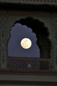 the full moon is seen through an archway