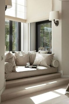 a window seat in the corner of a living room with pillows and blankets on it