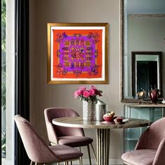 a dining room with chairs and a table in front of a painting on the wall