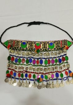 * This traditional classic necklace is an epitome of tradition. The tribal choker statement features three layers, each embellished with multicolour glass stones. * The style of the necklace is inspired by the Kuchi style of ornaments, as adorned with floral motifs and vintage coins dangling at the bottom. * The golden silver hues are complementing the vibrant glass stone inlays and elements at the top and bottom. The tribal necklace is a traditional fashion jewelry statement, festooned with met Traditional Metal Necklaces For Celebrations, Traditional Adjustable Necklaces With Colorful Beads, Traditional Adjustable Necklace With Colorful Beads, Traditional Adjustable Jewelry With Colorful Beads, Traditional Jewelry With Colorful Beads And Adjustable Fit, Handmade Bohemian Necklaces For Traditional Ceremonies, Traditional Necklaces With Colorful Beads And Adjustable Fit, Adjustable Colorful Beads Jewelry For Festivals, Adjustable Colorful Beaded Festival Jewelry