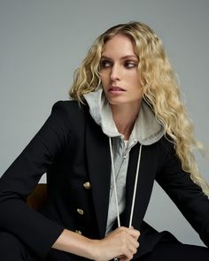 a woman sitting in a chair wearing a black jacket