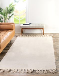 a living room with leather couches and a white rug on the wooden floor next to a window