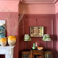 a living room with pink walls and two vases on top of the fireplace mantel