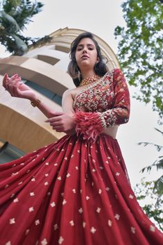 This gorgeous red lehenga is paired with a one shoulder printed blouse with feather work on the sleeve hem and mirror work on the neckline. Red And Golden Lehenga, Mendhi Ideas, Red Wedding Lehenga, Modern Blouse Designs, Golden Lehenga, Sequin Lehenga, Modern Blouse, Reception Outfits, 26 December