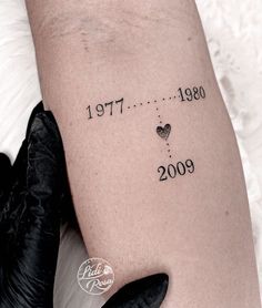 a person with a tattoo on their arm that reads date 2009 and has hearts in it