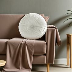 a living room with a brown couch and white pillow on it's side table