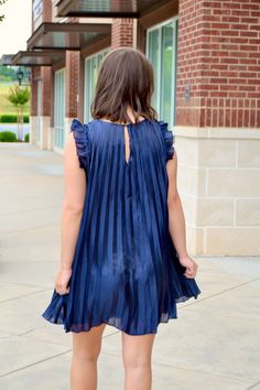 Navy sleeveless pleated dress with ruffle trim around the shoulders and a back button close, lined Sizes S, M and L Fabric: 100% polyester