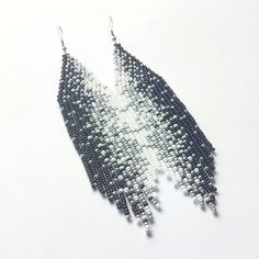 These long beaded earrings are inspired by the black, white and silver patters. Handcrafted with meticulous attention to detail, they exude timeless sophistication. Perfect for adding a touch of celestial charm to any ensemble, these earrings are sure to become a cherished addition to your jewelry collection. Dimensions: - Length: 13 cm (5 inches) - Width: 3 cm (1.2 inches) White Bohemian Beaded Earrings With Black Beads, Bohemian White Earrings With Black Beads, White Bohemian Beaded Earrings With Silver Beads, Bohemian White Beaded Earrings With Silver Beads, Bohemian Black Earrings With Silver Beads, Long Beaded Earrings, Long Chandelier, Beaded Fringe Earrings, Beaded Fringe