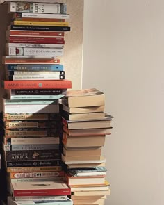 a stack of books sitting on top of a wooden floor next to a window sill