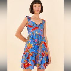 Blue Macaw Party Mini Dress Is Here With A Fresh Fit, A Cute Neckline, And The Print Is Something To Love Now And Wear On Repeat. Slim Fit Sweetheart Neckline Smocked Back Bodice Center Front Non-Functional Button Placket Layered Skirt Side Seam Pockets Vibrant Tropical Print Dress For Garden Party, Vibrant V-neck Dress With Tropical Print, Blue V-neck Dress With Vibrant Print, Blue Tropical Sleeveless Sundress, Vibrant Sleeveless Ruffled Dress, Vibrant Sleeveless Dress With Ruffles, Tropical Ruffle Dress For Garden Party, Blue Tropical Dress For Party, Tropical Blue Dress For Party