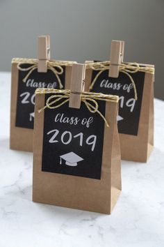 three brown paper bags with black and white graduation tags attached to them on a table