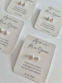 four pairs of pearl stud earrings on white cards with black ink and calligraphy in french