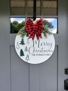 a merry christmas door hanger with a red bow and evergreen wreath on the front door