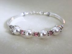 Swarovski crystals and pearls is perfect for your wedding, anniversary, or just because and is for sure to make as statement! It sits so comfortably on your wrist. This bracelet can be purchased with either light rose or crystal ab Swarovski crystals, both are lovely... It's made with four 8mm white swarovski crystal pearls, four 4mm light rose swarovski crystals along with pewter daisy and cone shaped spacers. It closes with a secure lobster claw clasp. Matching necklace: https://www.etsy.com/l Cord Bracelet Diy, Pearl Bracelet Wedding, Crystal Wedding Jewelry, Bridal Party Jewelry, Maid Of Honor Gift, Bachelorette Gift, Bracelet For Her, White Pearl Bracelet, Bridesmaid Pearls