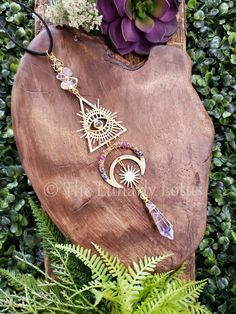 a necklace with an all seeing eye on it sitting next to a potted plant