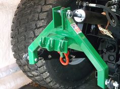 the front end of a green vehicle with two chains on it's back tire