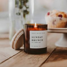 a candle sitting on top of a wooden table next to a muffin