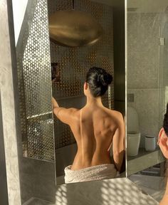 a woman taking a selfie in front of a mirror with her back turned to the camera