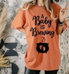 a woman wearing an orange baby is brewing t - shirt and black leggings