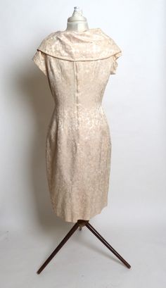 "Very pretty dress made of creamy heavy taffeta satin fabric with a tinge of pink. The fabric has a floral design. Grand shawl collar and a bow under the bust. The dress has a metal zipper up the back and is carefully concealed with a flap so it remains invisible. The zipper ends just below the collar. In excellent condition. Measurements are approximate: Bust - 38\", Waist - 29\", Hips - 45\". Modern-sized 10." Elegant Cream Vintage Dress With Fitted Bodice, Elegant Vintage Cream Dress With Fitted Bodice, Feminine Fitted Vintage Dress For Formal Occasions, Vintage Cream Satin Dress, Elegant Vintage Dress With Fitted Bodice, Silk Vintage Dress For Formal Occasions, Elegant Lined Dress For Vintage Fashion, Vintage Silk Dress For Formal Occasions, Fitted Silk Dress For Vintage Events