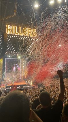 a large crowd at a concert with confetti thrown in the air and fireworks