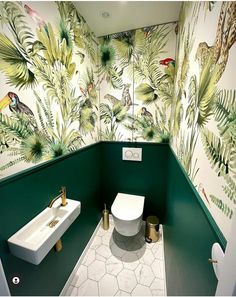 a bathroom with green and white wallpaper has a toilet, sink, and mirror