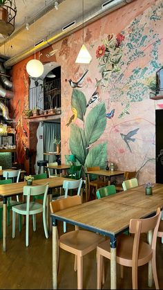 the interior of a restaurant with tables and chairs in front of a mural on the wall