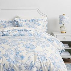 a bed with blue and white comforters in a bedroom next to a night stand