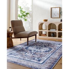 a blue rug with an ornate design on the floor in front of a chair and bookcase