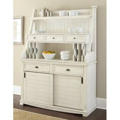 a white hutch with bowls and plates on it