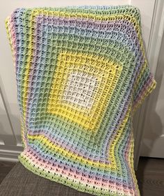 a multicolored crocheted blanket sitting on the floor