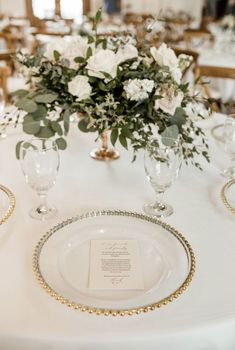 the table is set with white and gold place settings