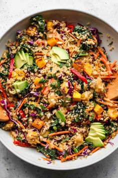 a white bowl filled with rice, vegetables and avocado on top of a table