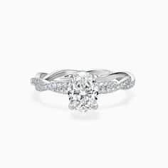 a white gold engagement ring with an oval cut diamond in the center and pave set shoulders