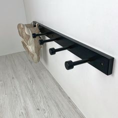 a pair of shoes hanging on a wall next to a shoe rack with two black handles