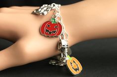 A collection of silver plated Halloween themed charms combined with five enameled Jack o'Lantern charms have been dispersed around a shimmering silver plated bracelet chain in this handmade charm bracelet. This Halloween charm bracelet is then completed with a lobster clasp and a 1/2 inch of chain at the end for adjustable sizing. Charms in this bracelet include five enameled jack o' lantern charms, haunted house charm, grim reaper charm, masquerade mask charm, and screaming skull charm. I also Halloween Novelty Jewelry Bracelet, Halloween Novelty Bracelet, Halloween Themed Jewelry For Costume Party, Themed Metal Jewelry For Halloween, Themed Jewelry For Halloween Costume Party, Halloween Gift Charm Bracelet, Novelty Silver Halloween Bracelet, Novelty Silver Bracelet For Halloween, Silver Halloween Novelty Bracelet