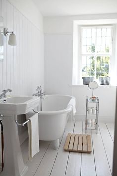 a white bathroom with two sinks and a bathtub in the middle of the room