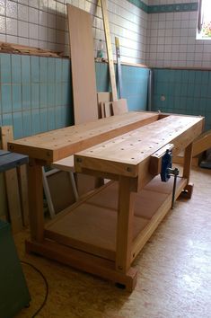 a wooden workbench in the middle of a room with blue tiles on the walls