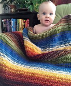 a baby wrapped in a multicolored blanket