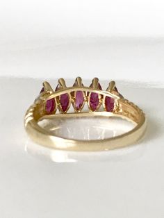 Surprise her with this vintage ruby yellow gold ring in 14k. The sparkling design of this July birthstone ring has 5 Marquise shaped real rubies with 2 tiny diamonds on a scalloped band. The genuine ruby ring is full of character with the scalloped band and, crescent moons on the sides. This luscious ruby ring with its gorgeous pinky red color is a classic timeless piece, and would make a great anniversary present. The size 7 ring is in excellent condition! Rubies are the gemstone for the 15th w Fine Jewelry Marquise Ruby Ring With Multi-stone, Marquise Multi-stone Ruby Ring, Marquise Multi-stone Ruby Ring In Fine Jewelry Style, Ruby Birthstone Ring Marquise Cut For Anniversary, Vintage Multi-stone Ruby Ring, Ruby Marquise Cut Birthstone Ring For Anniversary, Marquise Cut Ruby Birthstone Ring For Anniversary, Marquise Ruby Ring With Prong Setting In 14k Gold, Anniversary Ruby Birthstone Ring With Marquise Cut