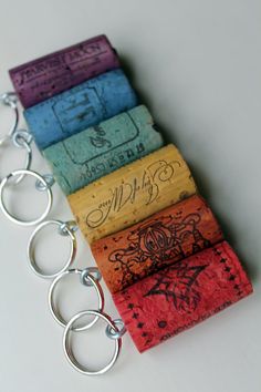 four different colored wine corks sitting in a row on a white surface with metal keychains